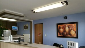 A reception area with a counter, a water dispenser, a telephone, a television, and a framed artwork on the wall. - Budget Inn Express Douglas (Douglas)