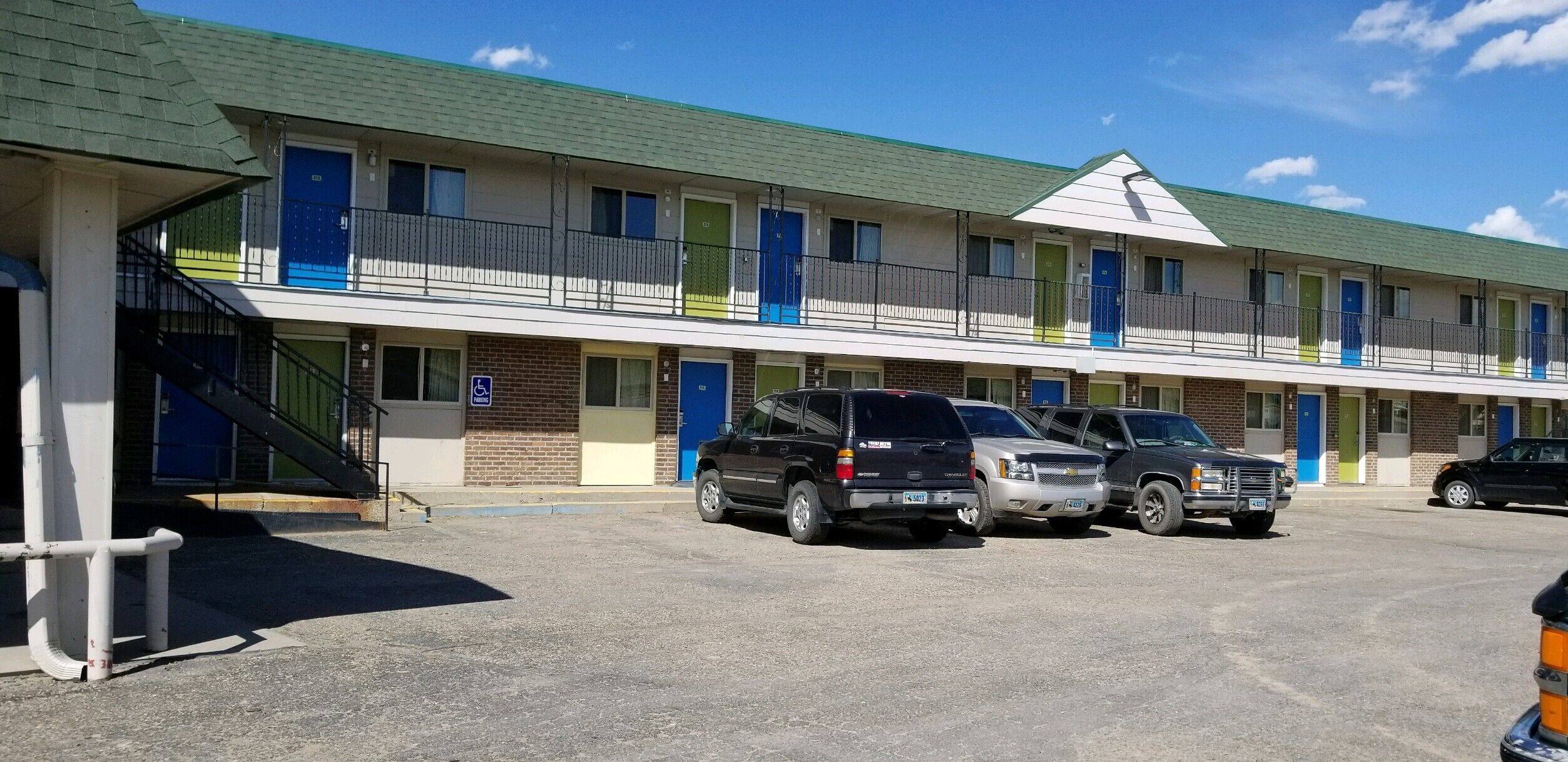 A motel with multiple rooms, a parking lot, and a ramp leading to the entrance.