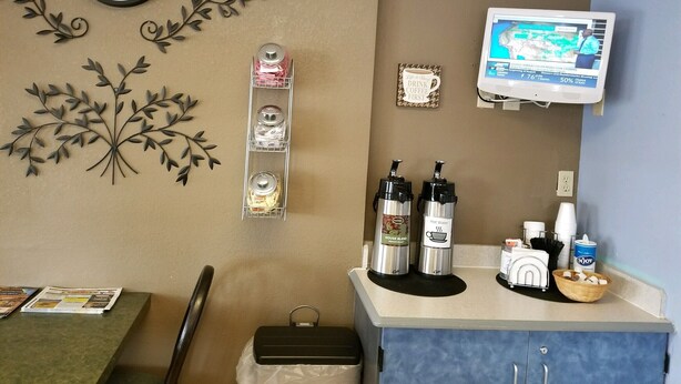A room with a clock, a wall-mounted TV, a coffee station, and decorative wall art. - Budget Inn Express Douglas (Douglas)