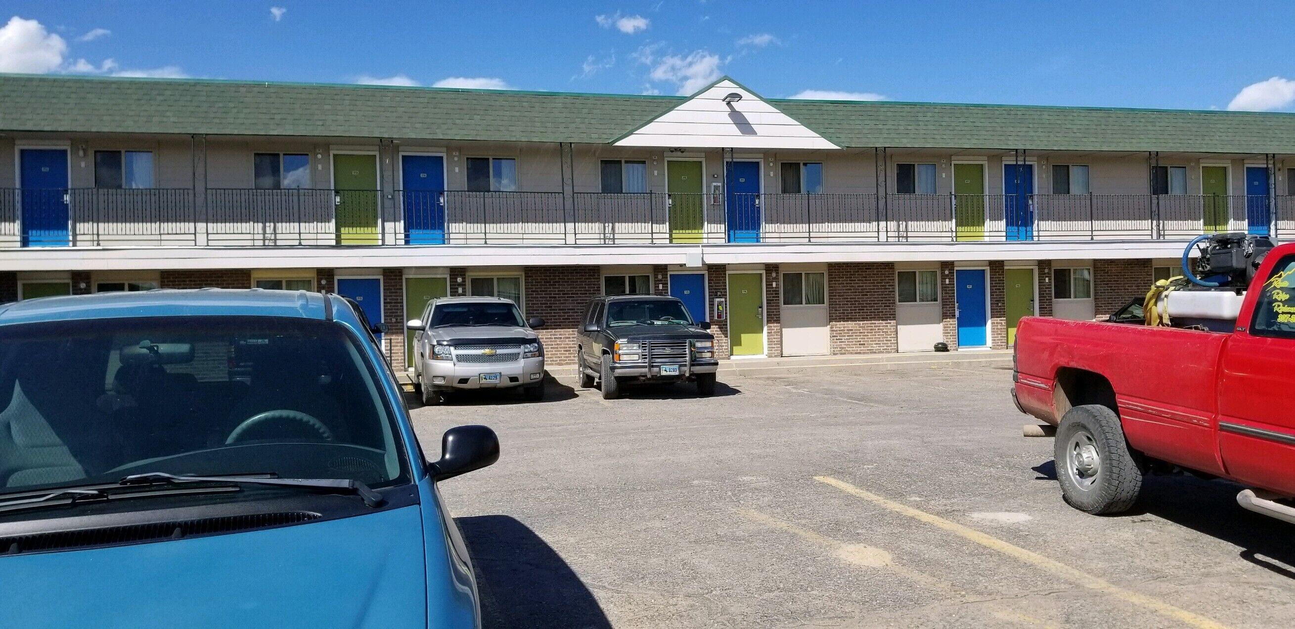 A motel with multiple rooms, a parking lot, and several parked vehicles.