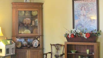 A traditional room with a wooden cabinet, a chair, a bookshelf, and a framed picture on the wall.