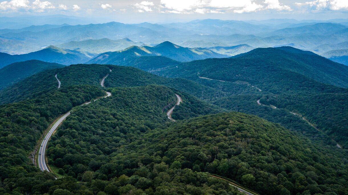 A winding road through a mountainous area with dense forests.