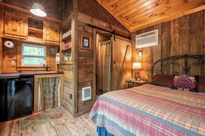 A rustic wooden room with a bed, a small desk, and a window. - The Owl's Perch (5 inch clearance needed) (Robbinsville)