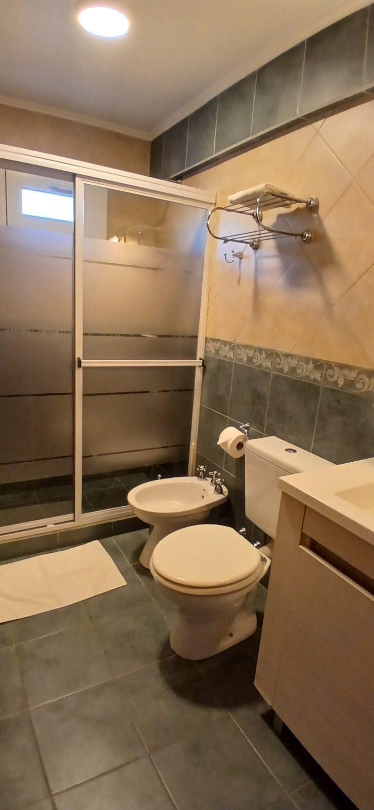 Et badeværelse med bruser, toilet og håndvask.