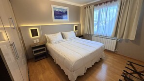 A hotel room with a large bed, bedside tables, a view of the outdoors, and a mounted picture on the wall. - La Posta Apart (Ushuaia)