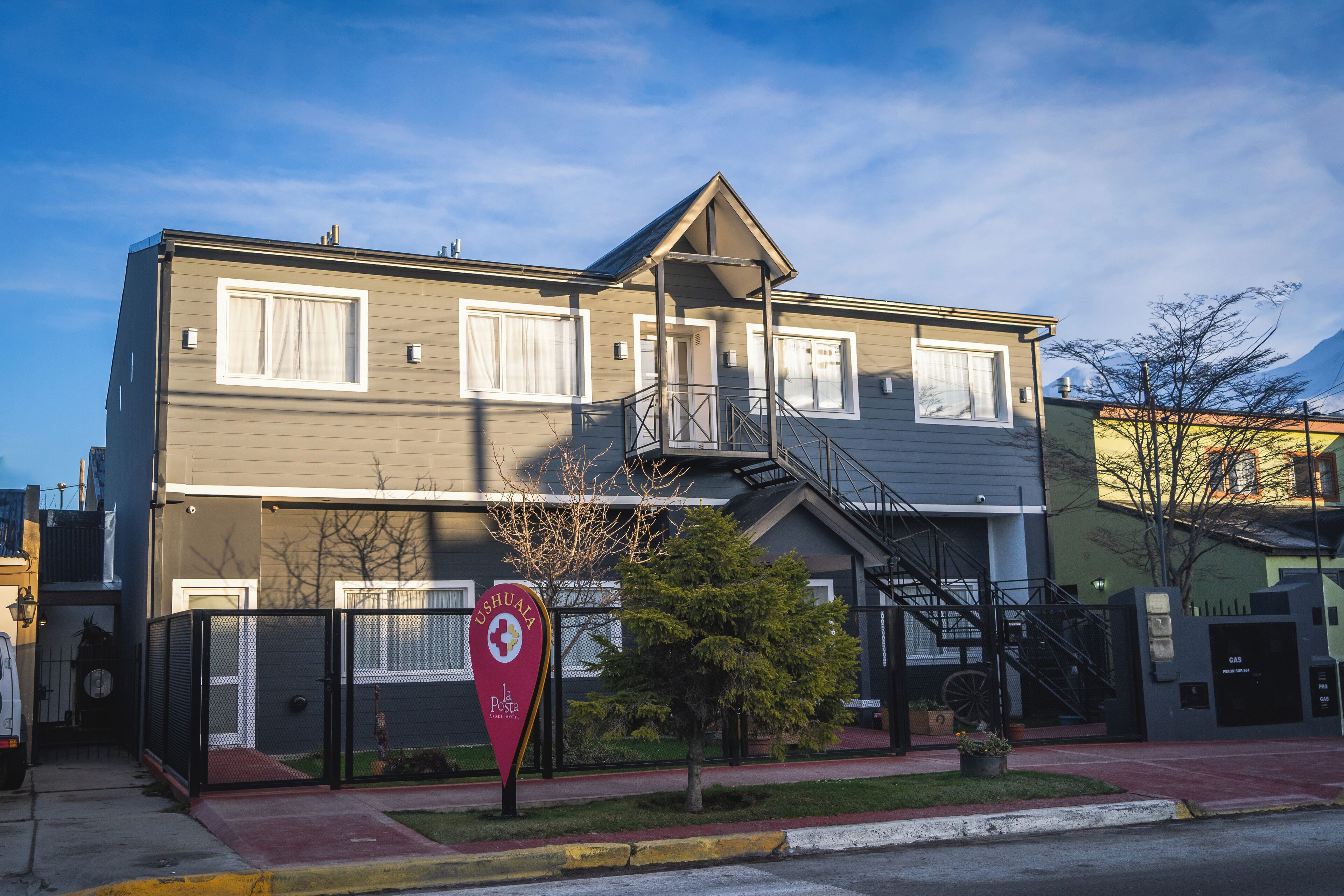 Ein zweistöckiges Gebäude mit Feuerleiter, geschlossenem Eingangsbereich und einem Schild, das angibt, dass es sich um eine Poststelle handelt.