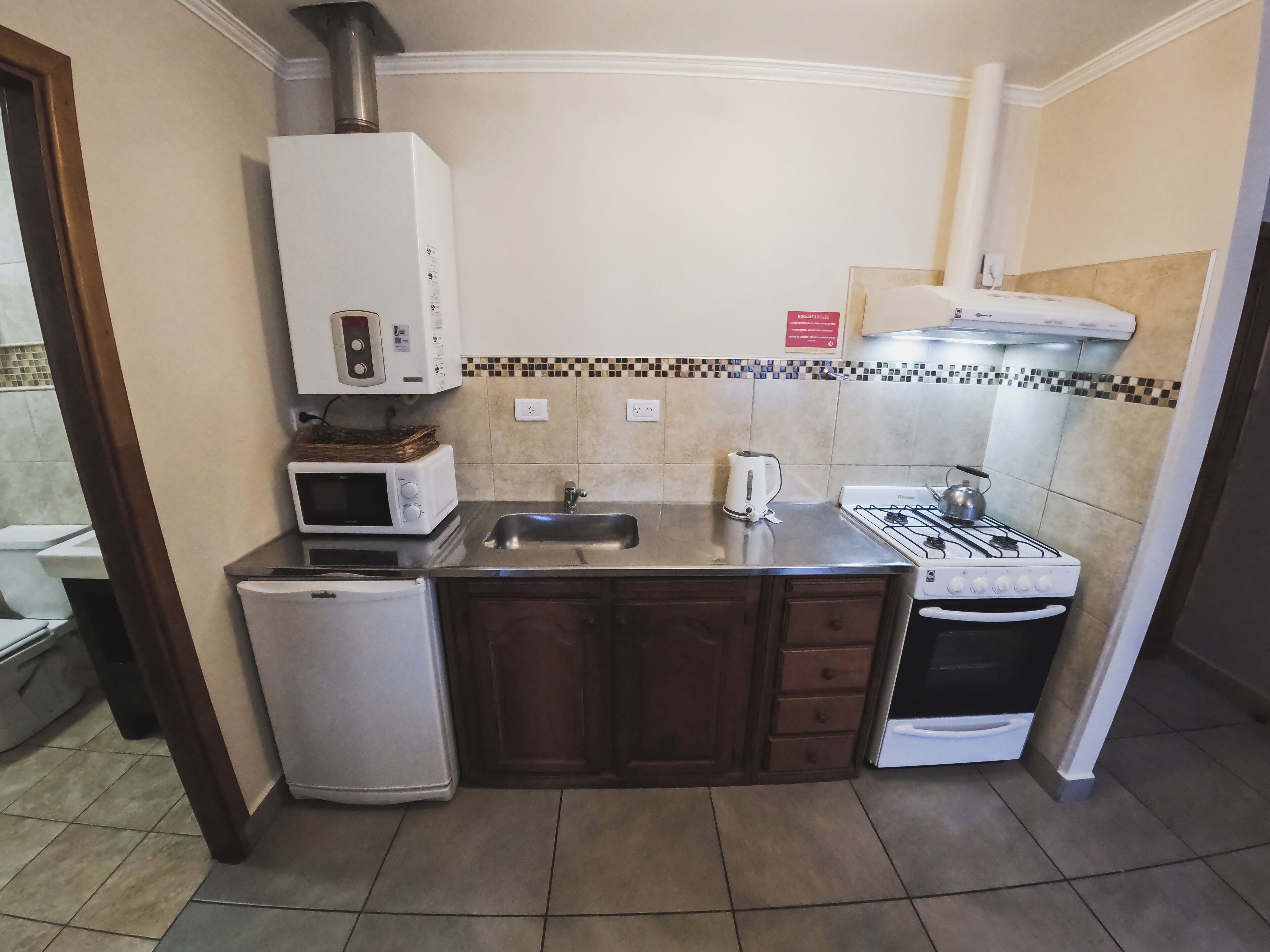 A compact kitchen with a refrigerator, microwave, stove, sink, and cabinets.