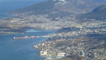 Vista aérea de un pueblo costero con un puerto, edificios y una montaña al fondo.