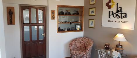 Een kamer met een houten deur, een stoel, een tafel met een lamp en een bordje met de tekst 'La Posta Hostelpart'.