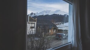 A view through a window of a building with a snow-capped mountain in the background. - La Posta Apart (Ushuaia)