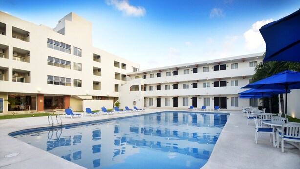 A modern hotel with a central swimming pool, multiple balconies, and outdoor seating areas. - Hotel Bonampak (Cancun)
