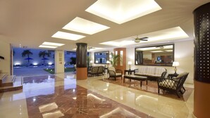 A spacious lobby with a polished marble floor, a seating area with sofas and armchairs, and a large mirror reflecting the room. - Hotel Bonampak (Cancun)