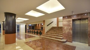 A modern lobby with a marble floor, a reception desk, a staircase, and an elevator. - Hotel Bonampak (Cancun)