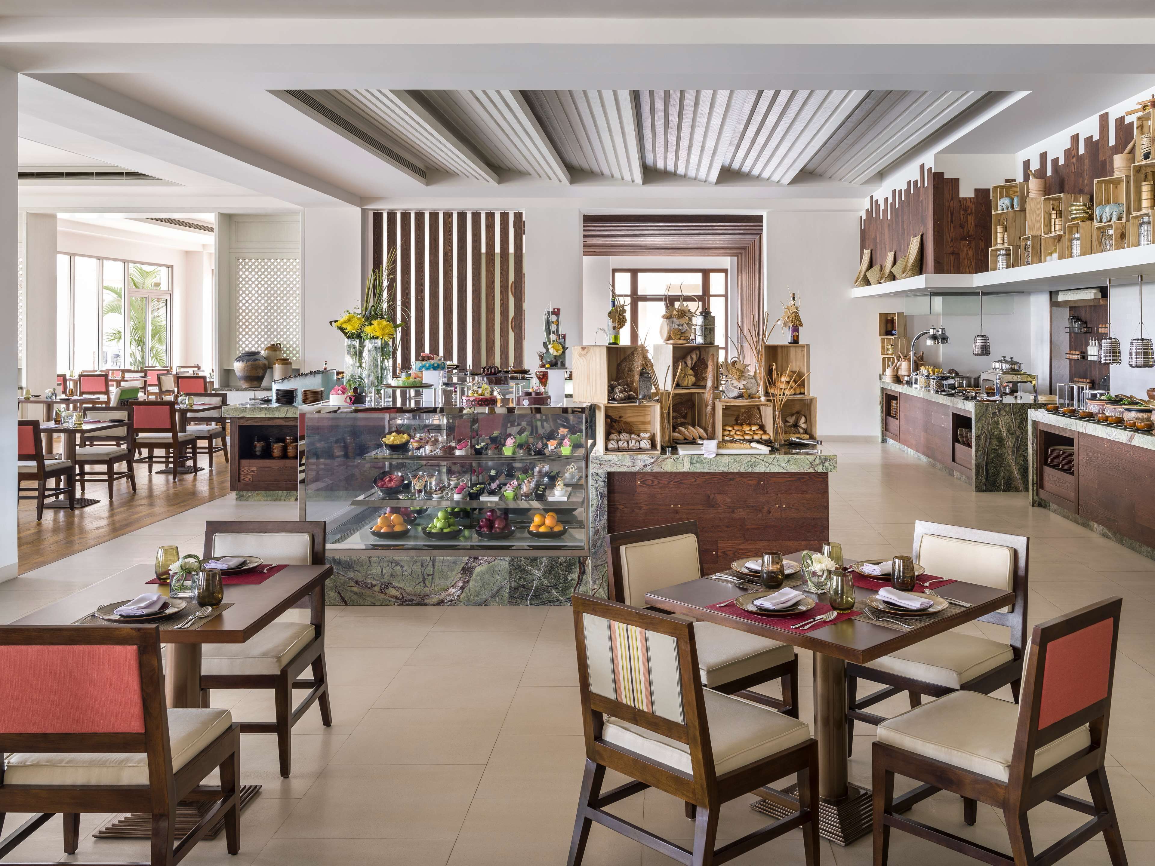 Un comedor moderno con mobiliario de madera, una isla central con exhibición de alimentos y un techo decorativo.