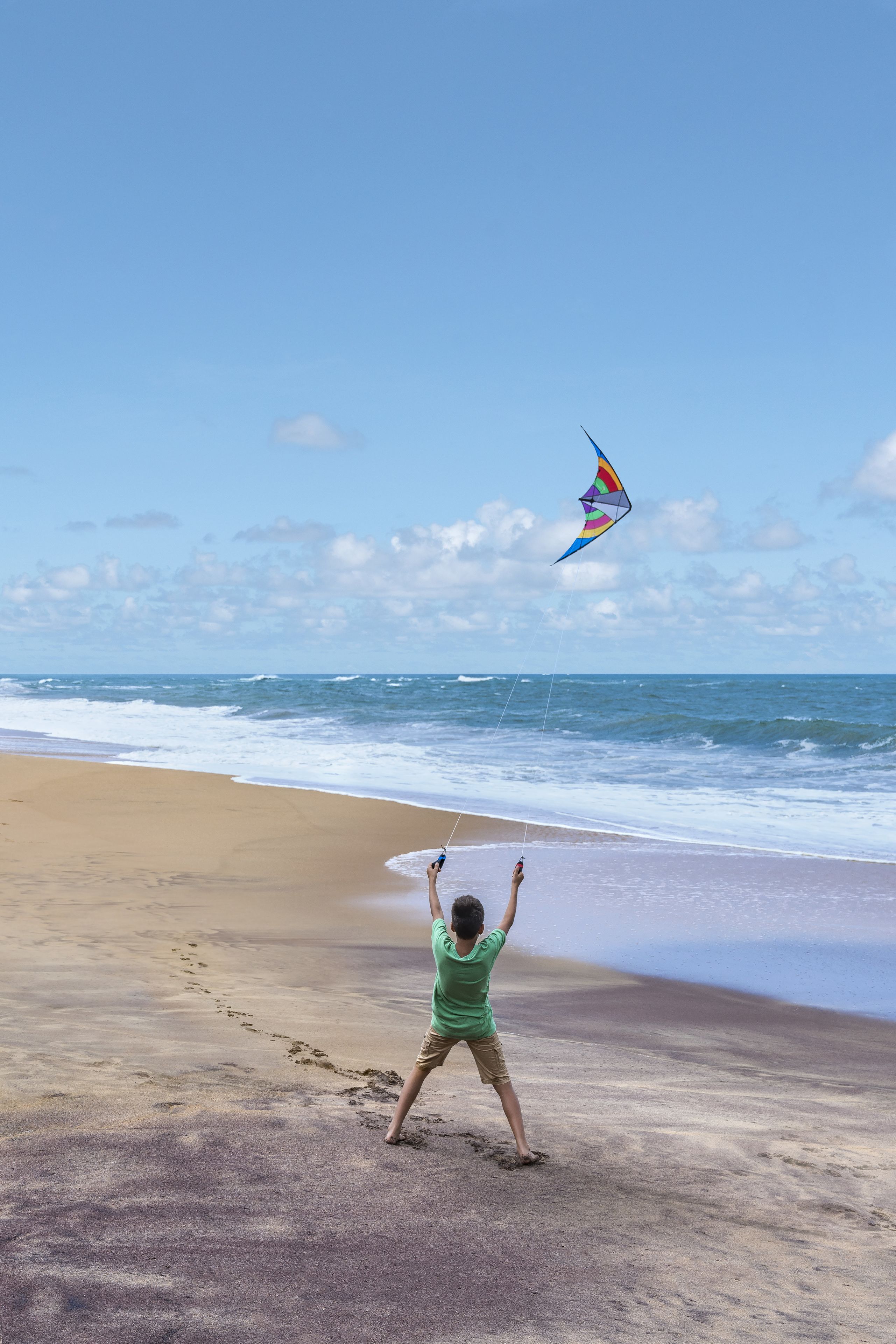 Una playa con una persona volando una cometa.