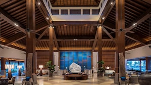 Un vestíbulo espacioso con techos altos, vigas de madera y una zona de estar central con una gran escultura decorativa.