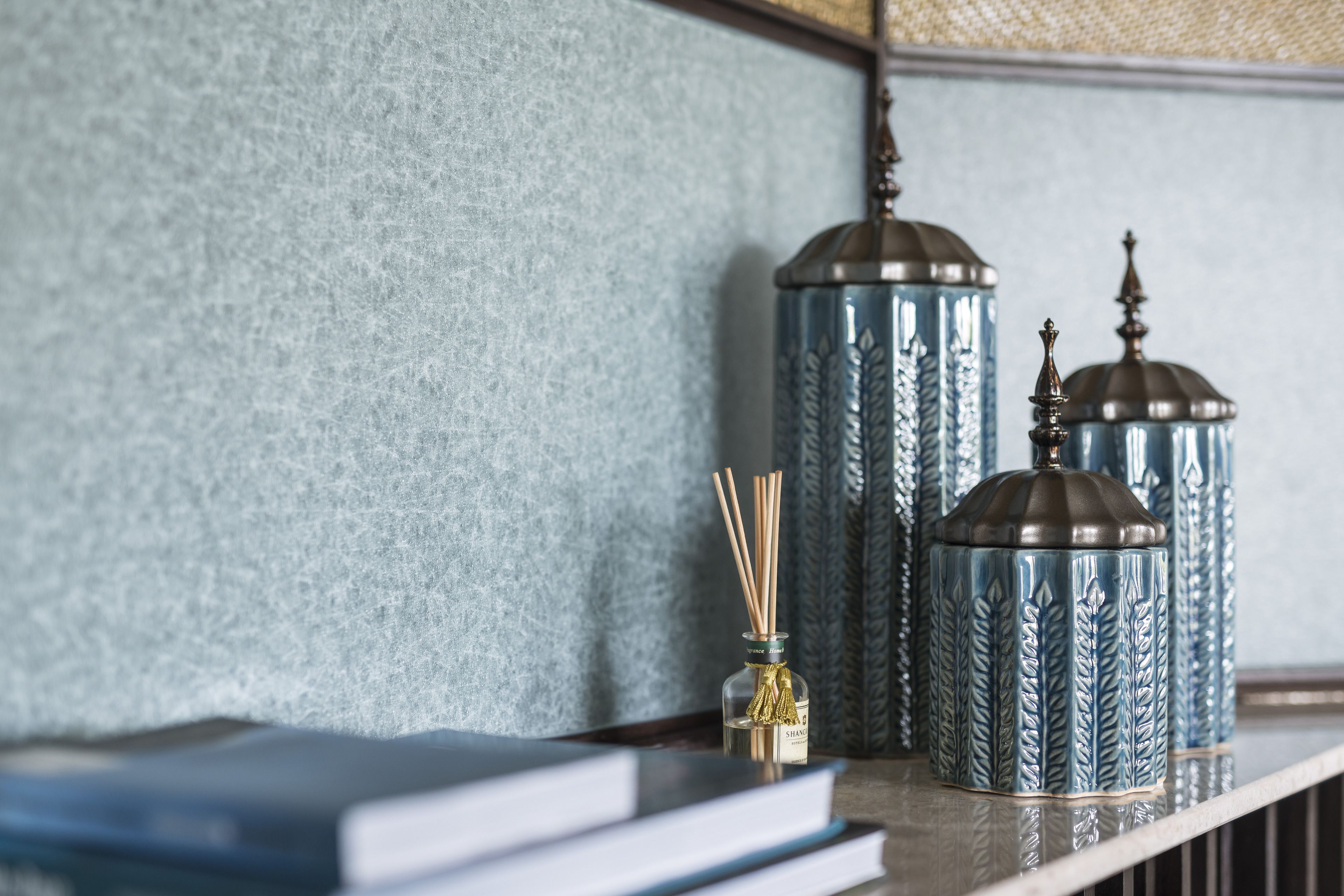 Uma prateleira com vasos decorativos e um difusor de aroma em vidro.