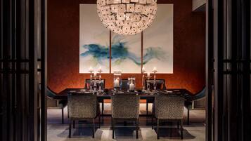 Un comedor con una lámpara de araña redonda, dos cuadros abstractos y una mesa preparada para cuatro.