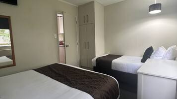 Habitación de hotel con dos camas, un escritorio, un armario y un espejo.