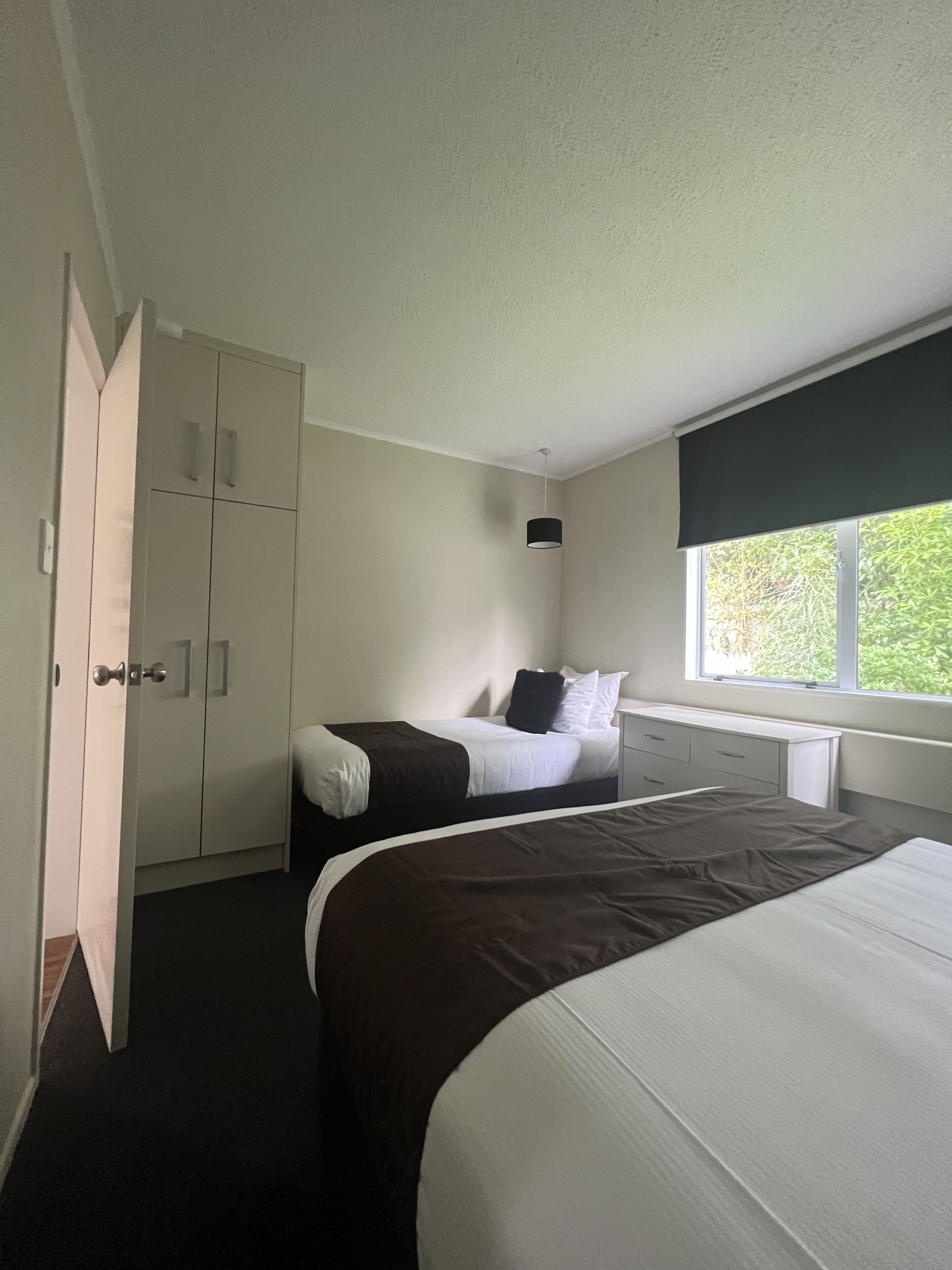 A hotel room with a large bed, a smaller bed, a desk, and a wardrobe.