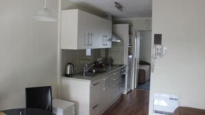 Une cuisine compacte avec des meubles blancs, un évier et une cuisinière. On y trouve également un coin repas avec une table et des chaises.