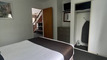 Ein Schlafzimmer mit Bett, Kleiderschrank, Schreibtisch und Stuhl.