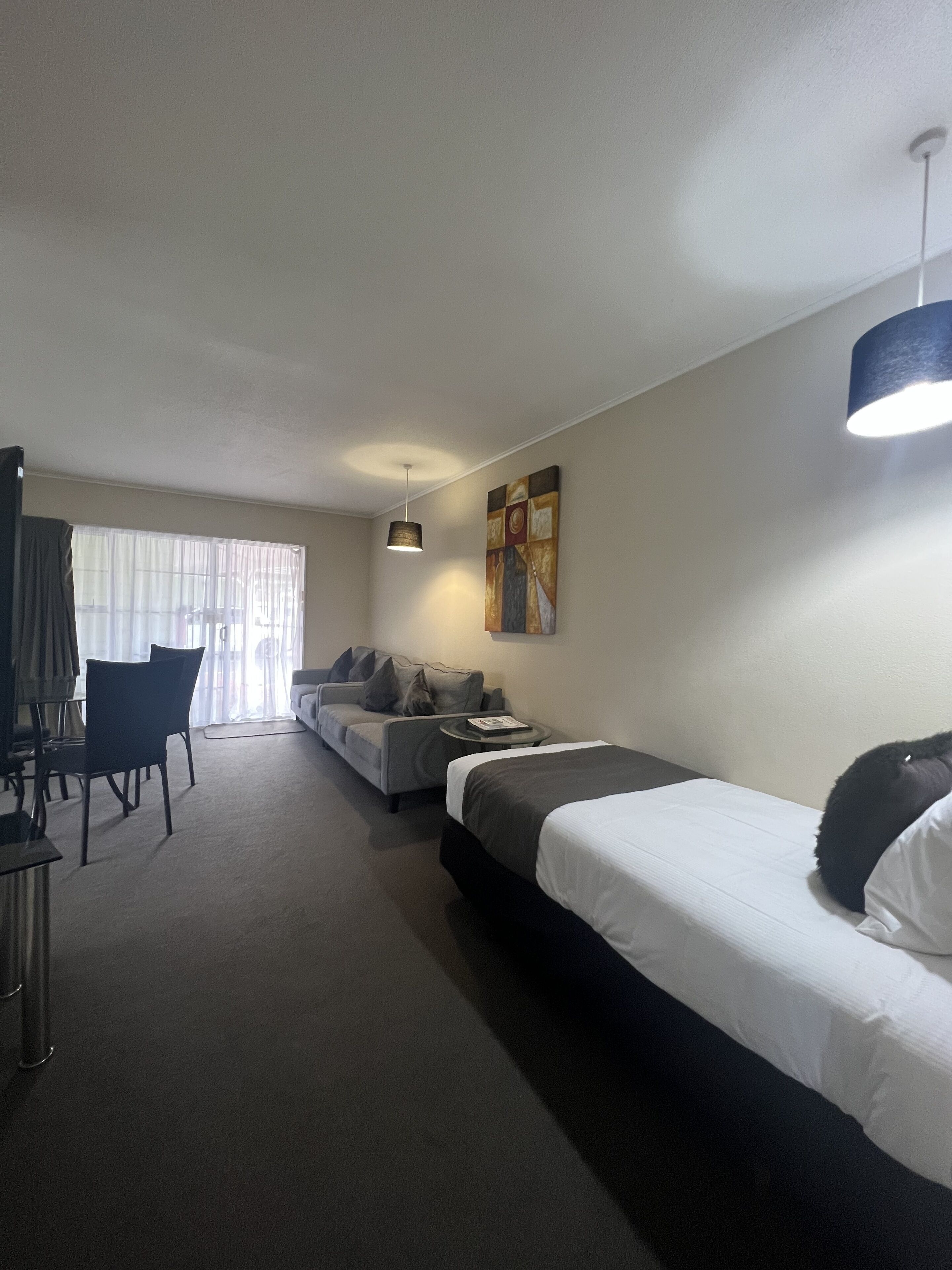A hotel room with a bed, a sofa, a desk, and a chair.