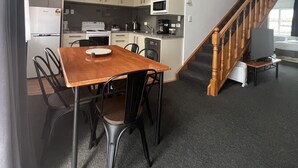 Une cuisine compacte comprenant une table à manger, des chaises et un four à micro-ondes. Un escalier mène à une chambre.