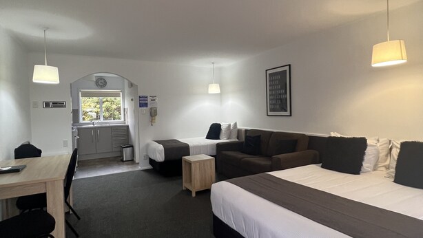 Une chambre d’hôtel avec un grand lit, un canapé, un bureau et une kitchenette.
