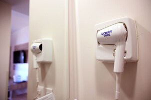 A hair dryer mounted on a wall, a power outlet, and a partially visible door.