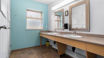 A bathroom with two sinks, a window, and a mirror.