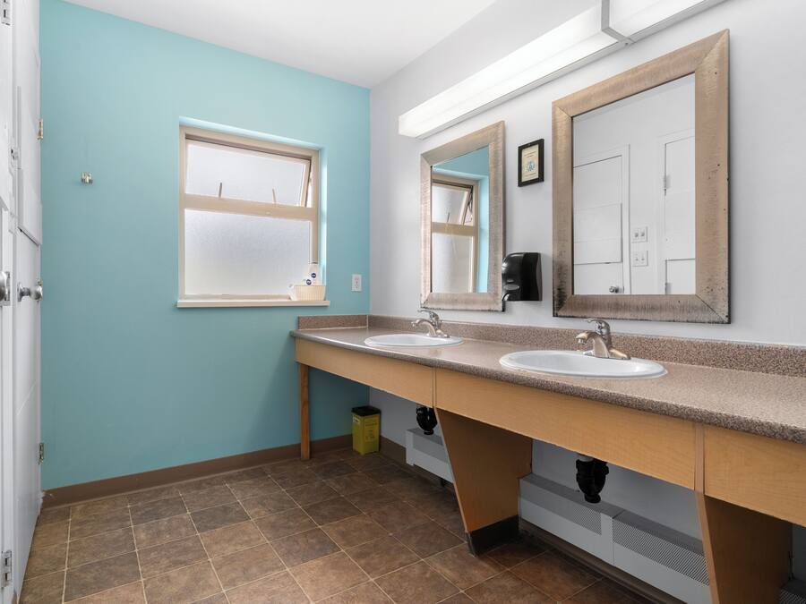 A bathroom with two sinks, a window, and a mirror.