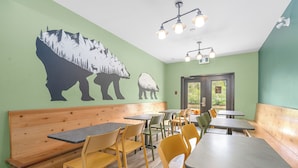 Un restaurante con paredes verdes, bancos y mesas de madera.