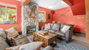 Una sala de estar acogedora con una pared de piedra, una chimenea y un sofá de cuero.