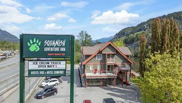 Señal del Squamish Adventure Inn con un logotipo verde, que indica la apertura de un carrito de helados el 1 de mayo.