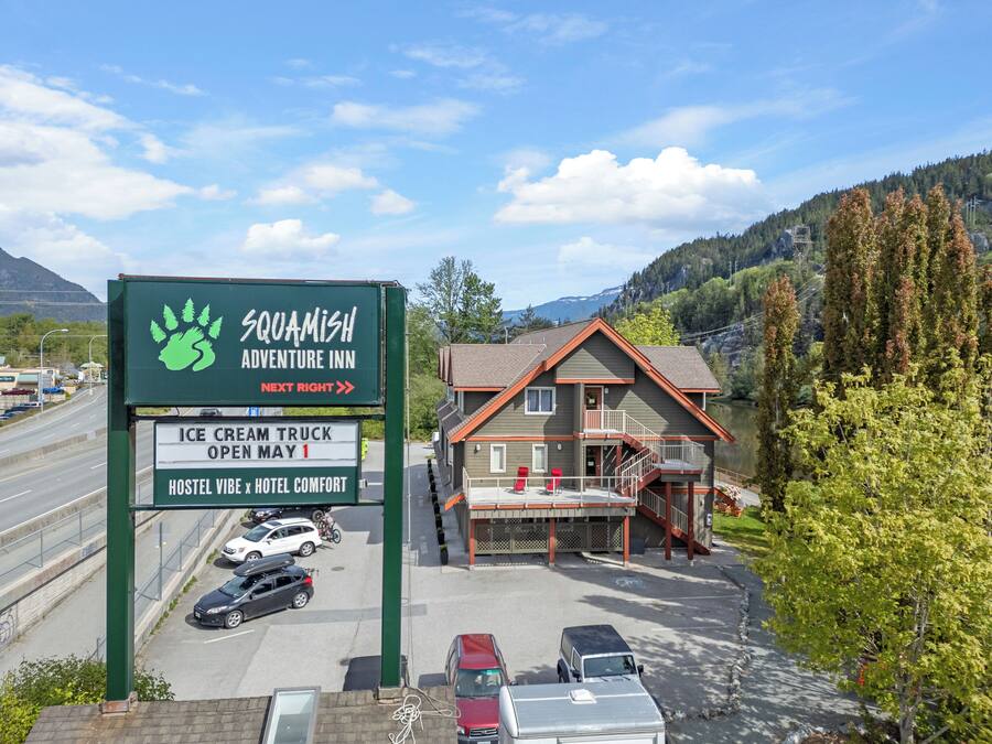 Señal del Squamish Adventure Inn con un logotipo verde, que indica la apertura de un carrito de helados el 1 de mayo.