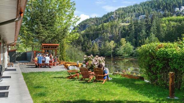 Un restaurante junto al lago con terraza, vistas al lago y una ladera boscosa al fondo.