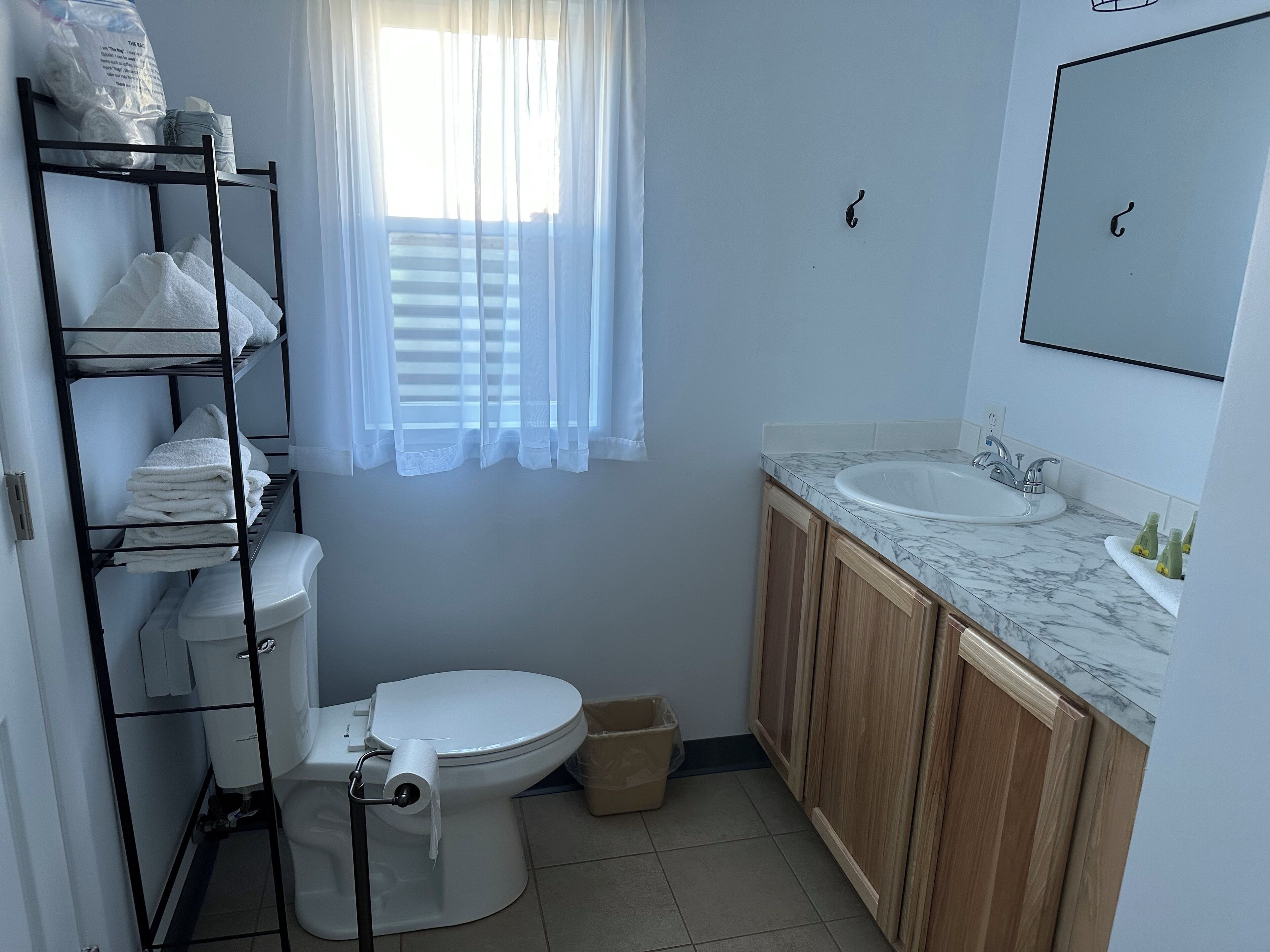 Un baño con inodoro, lavamanos y estantes con toallas.