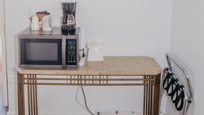 A compact kitchenette with a microwave, coffee maker, and a small shelf above the counter. - Lamplighter Lodge (Panguitch)
