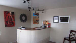A reception area with a curved white counter, a clock, and framed pictures on the wall. - Lamplighter Lodge (Panguitch)