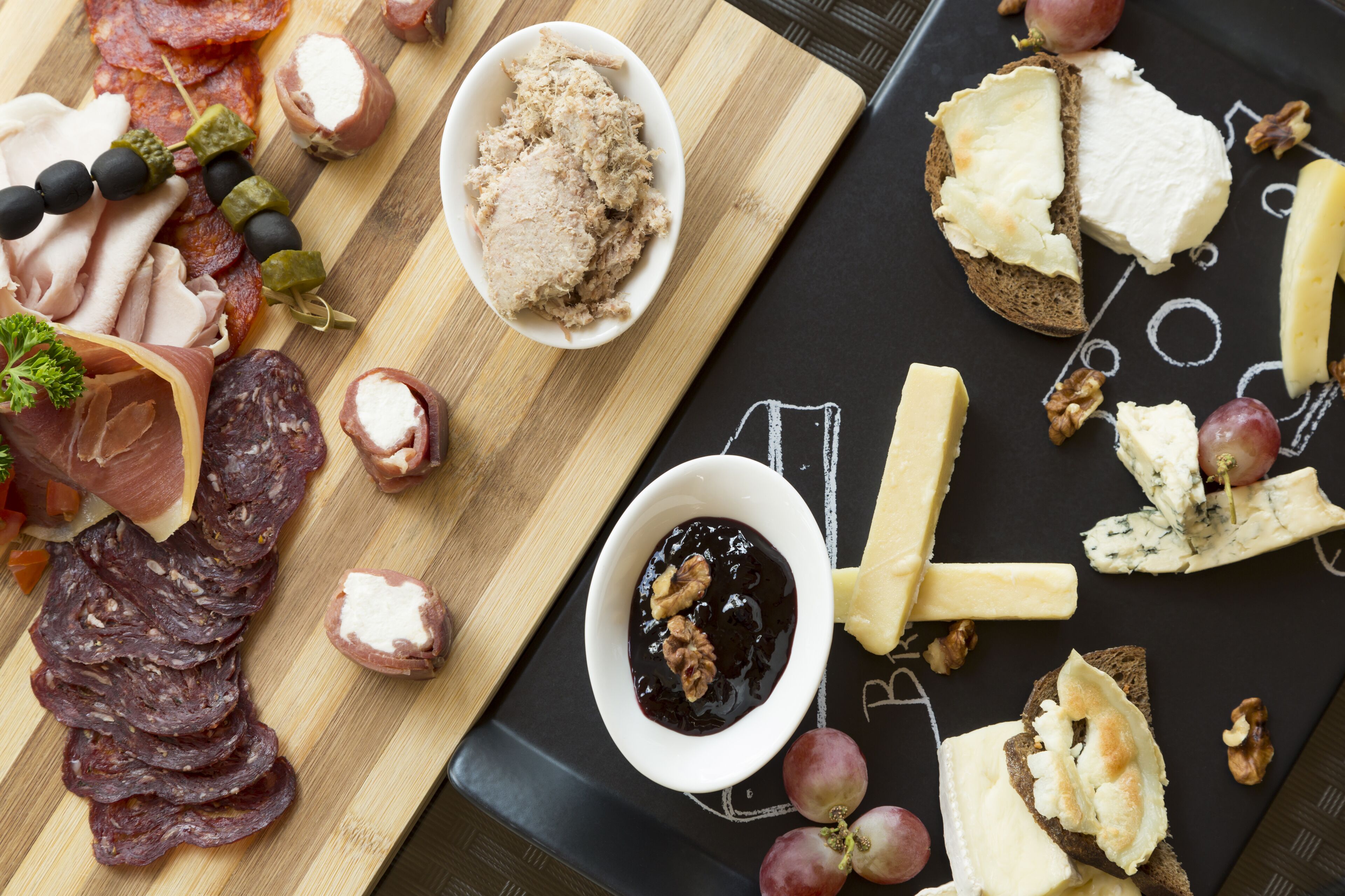 A charcuterie board with various meats, cheeses, and fruits.