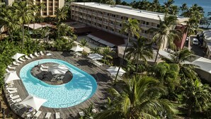 A resort with a large pool, palm trees, and a view of the ocean.