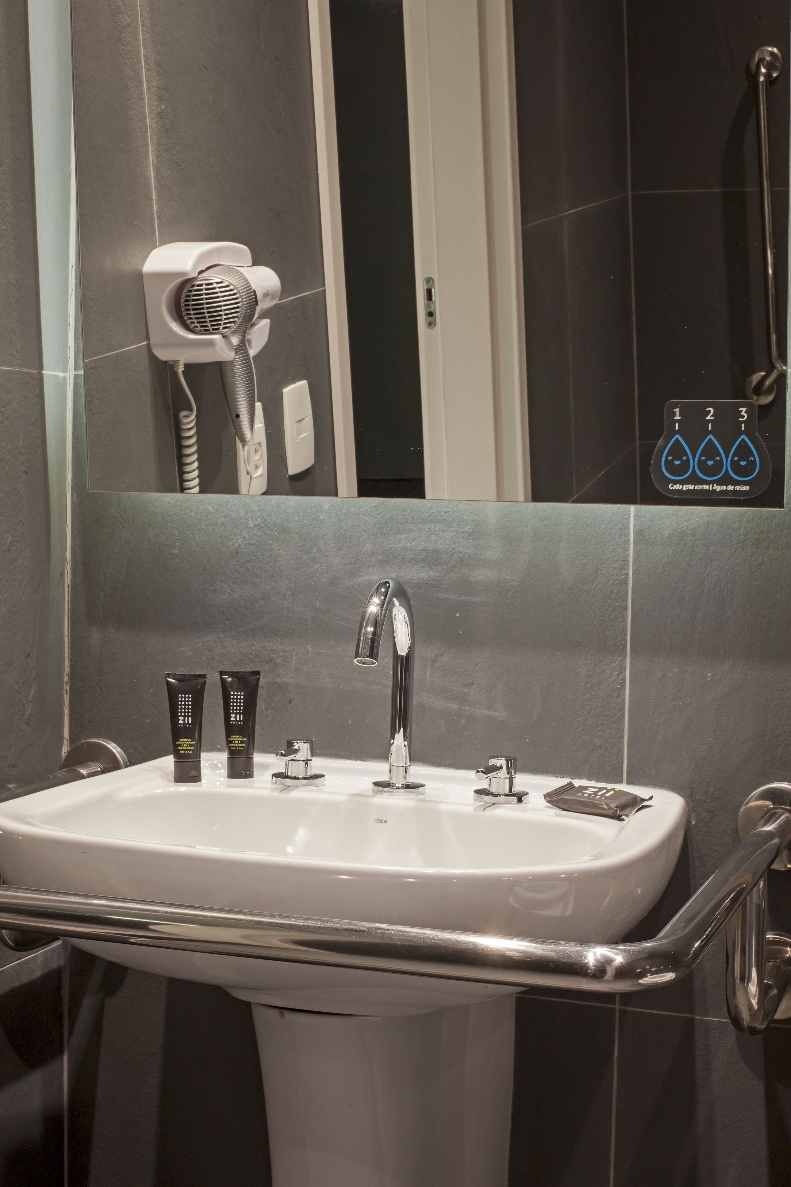 Une salle de bain avec un lavabo blanc, un sèche-cheveux et un miroir.
