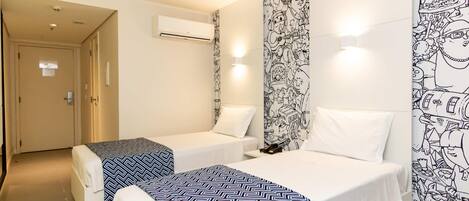 Habitación de hotel con dos camas, un mural en la pared, un equipo de aire acondicionado y una puerta.