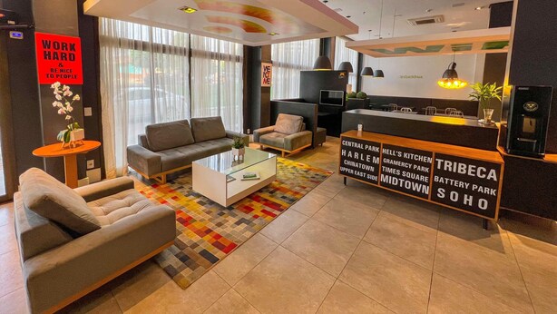 A modern hotel lobby with a sofa, armchair, coffee table, and a reception desk.