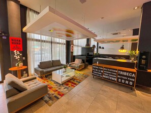 A modern hotel lobby with a sofa, armchair, coffee table, and a reception desk. - Ibis Styles Rondonopolis (Rondonopolis)
