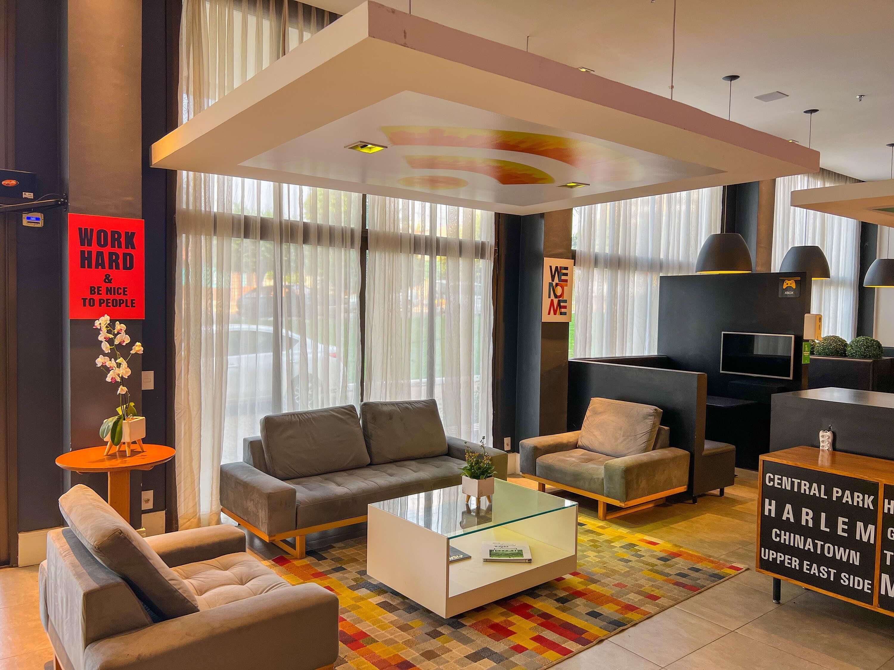 A modern hotel lobby with a sofa set, a glass coffee table, and a sign indicating the location as Central Park Harlem Chinatown Upper East Side.