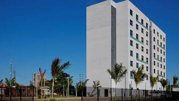 Un immeuble moderne à plusieurs étages, doté d’une façade plate, d’une série de fenêtres et d’une entrée fermée par un portail.