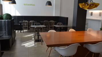 A modern restaurant interior with black and white furniture, pendant lighting, and a green wall sign.