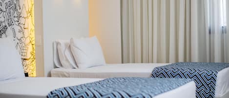 Habitación de hotel con dos camas, una lámpara de pared y una ventana con cortinas.